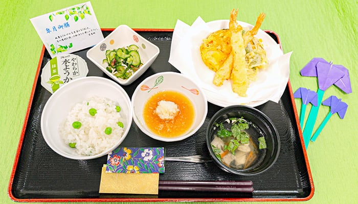 豆ご飯や天ぷら、きゅうりの酢の物水ようかんなどが並んだ5月の行事食「皐月御膳」の写真